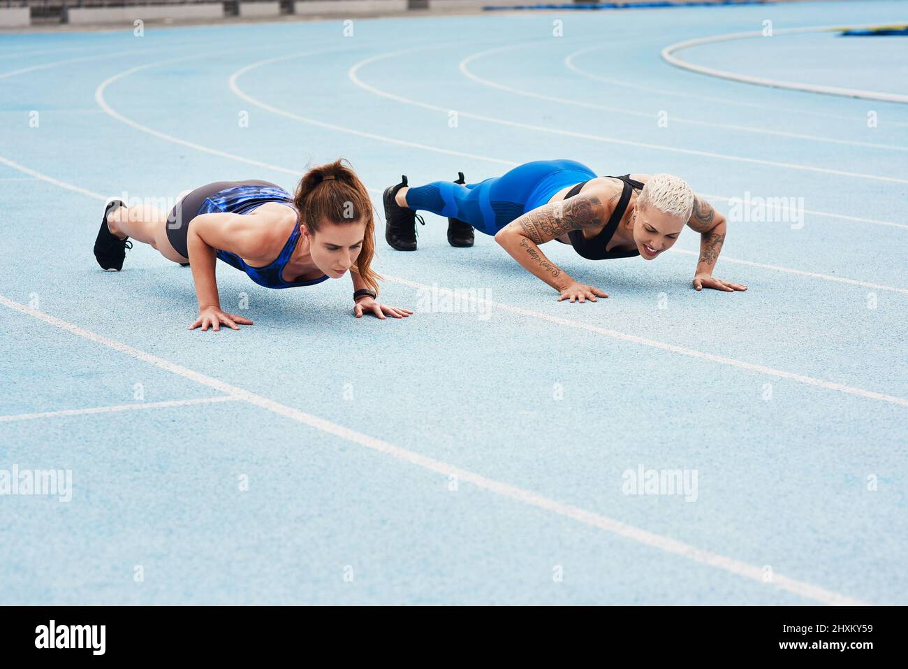 You ready. Full length shot of two attractive young female athletes doing pushups out on the track. Stock Photo