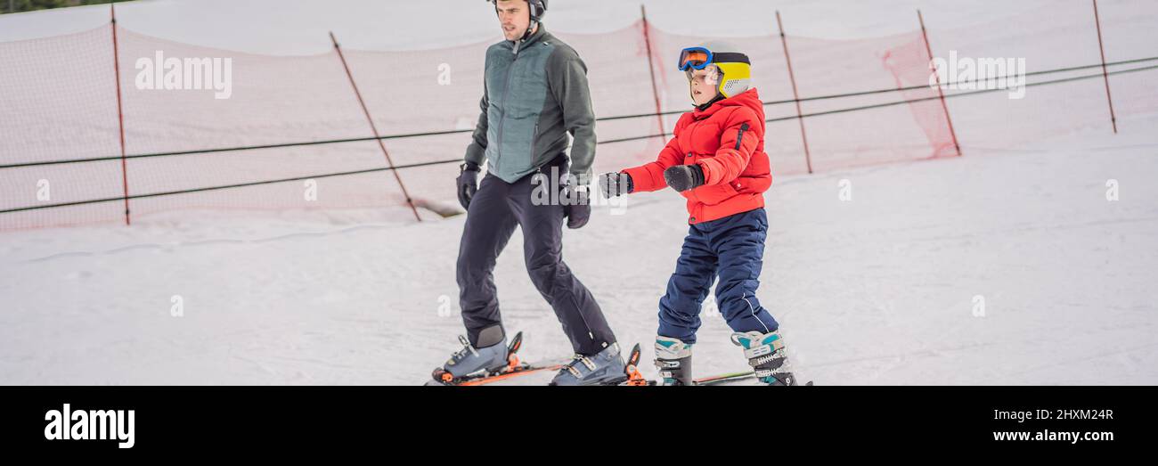 Boy learning to ski, training and listening to his ski instructor on the slope in winter BANNER, LONG FORMAT Stock Photo