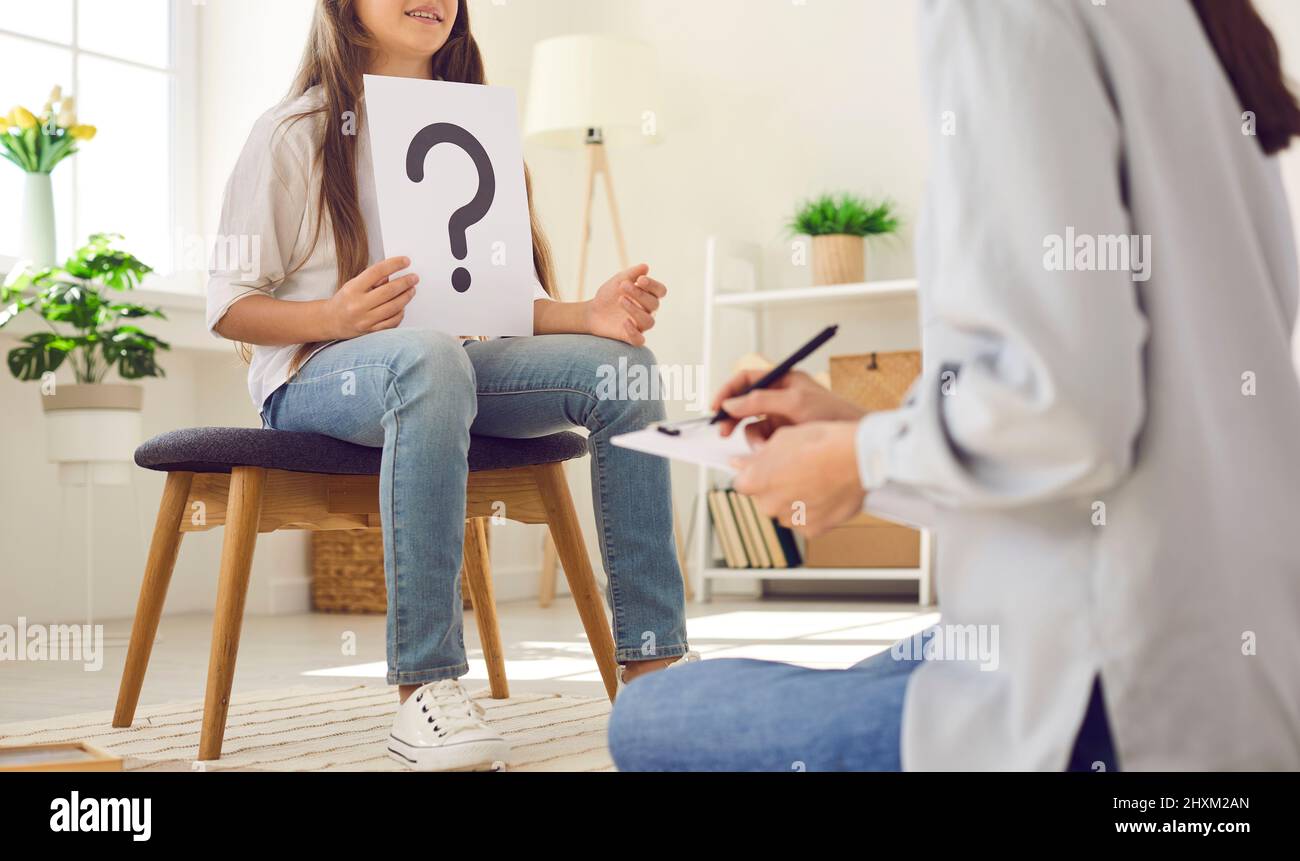 Psychologist or therapist interviewing a child who's holding a question mark card Stock Photo