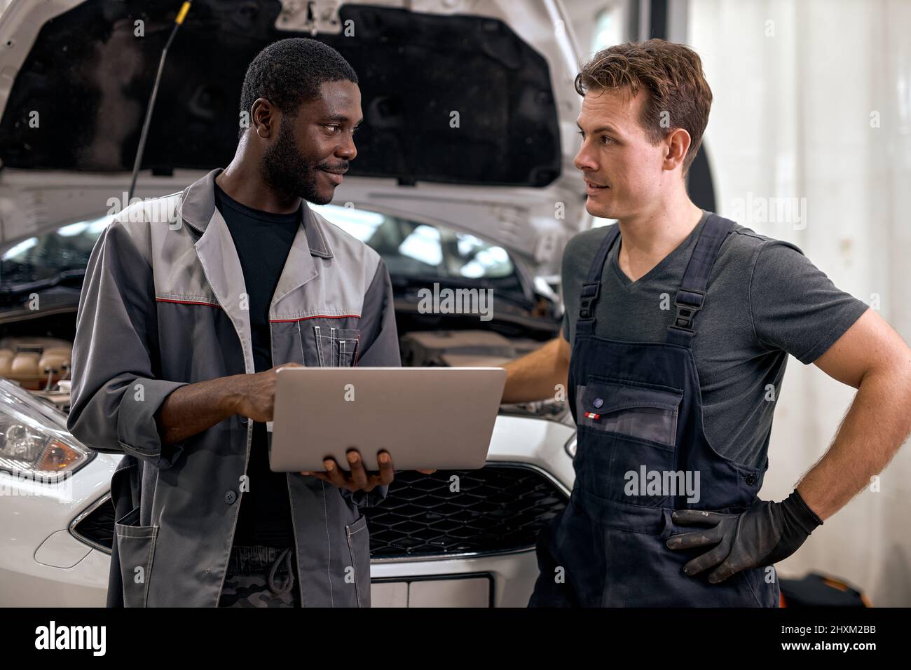 Computer Car Tuner Tech Computer Car Tuning. two Smiling auto mechanic testing a car engine ...