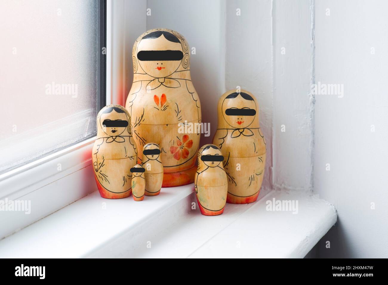 Family of Russian Dolls in a grouping on a window sill with their eyes blacked out so they cannot see Stock Photo