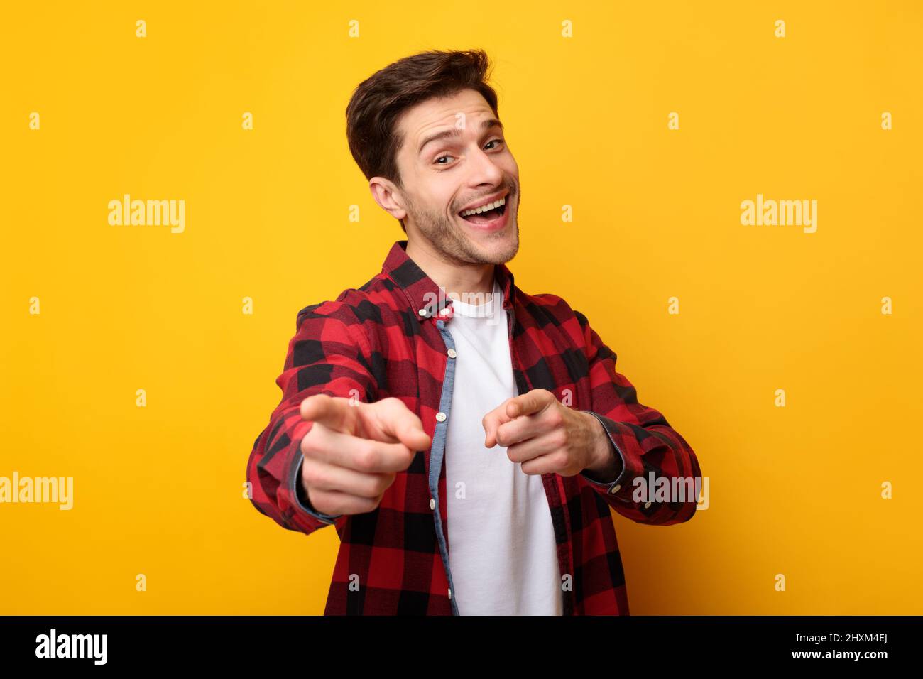 Happy young man pointing fingers at camera at studio Stock Photo
