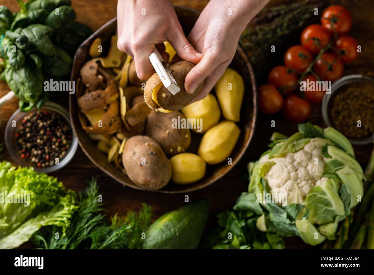 https://c8.alamy.com/comp/2HXM5B4/a-woman-is-peeling-potatoes-various-fresh-vegetables-lie-on-the-table-cooking-vegetarian-food-2HXM5B4.jpg