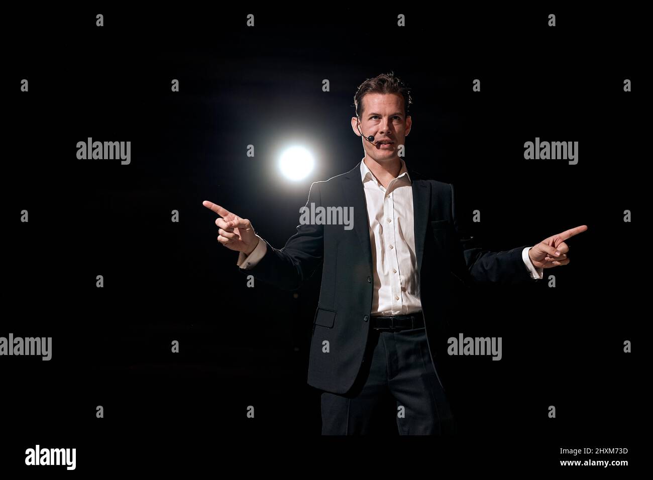successful man with microphone speaking at corporate business coaching and training auditorium conference room talking giving motivation training from Stock Photo