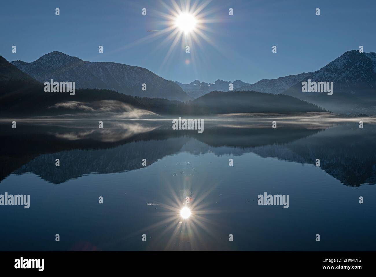 afternoon sun seen from Seewiese with fog rising from lake and Sarstein mountain in background Stock Photo