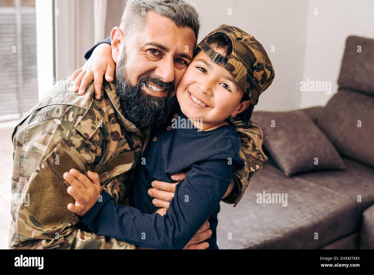 Military soldier father with son kid smiling on camera during home return - Family love US army Stock Photo