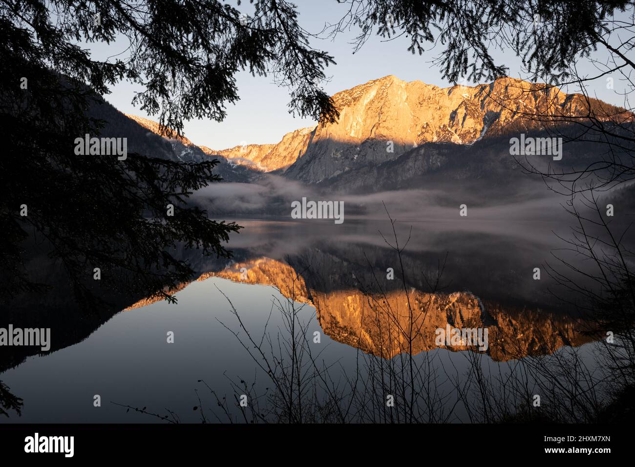 Trisselwand mountain reflecting in Altaussee lake on winter afternoon Stock Photo