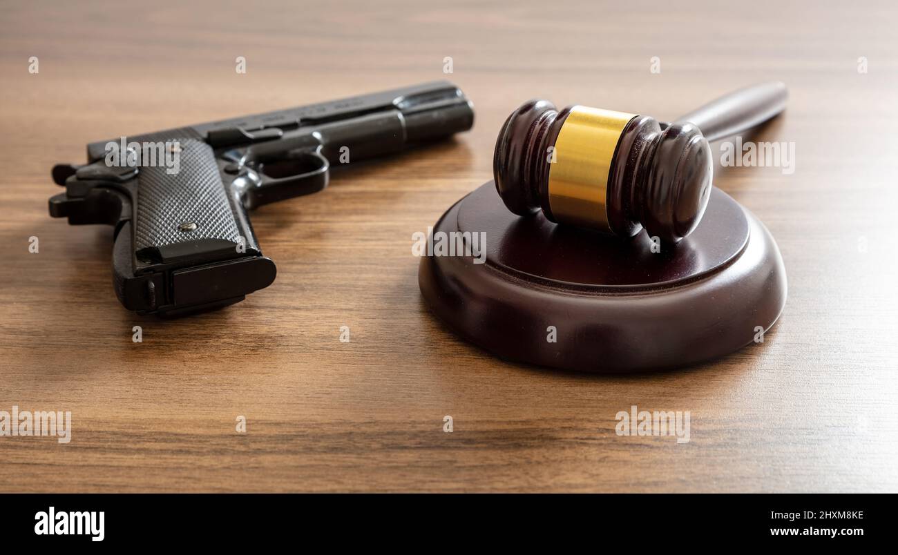 Crime, gun carry and use punishment concept. Judge gavel and handgun on lawyer office desk. Wooden courthouse table, close up view Stock Photo