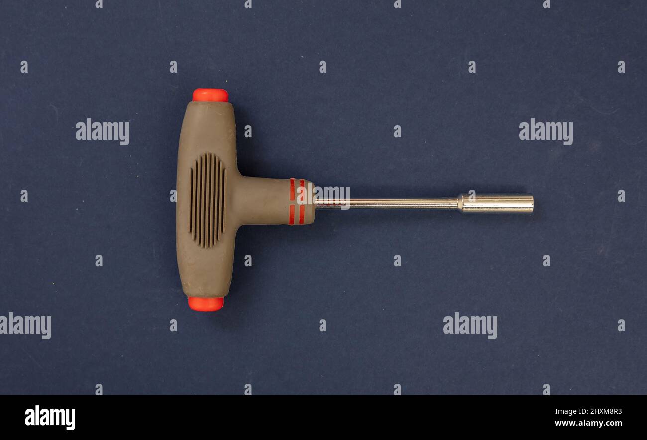 Allen wrench with brown color rubber handle on blue background. Hand tool, implement for repair, tighten, twisting screw. Overhead, close up view. Stock Photo