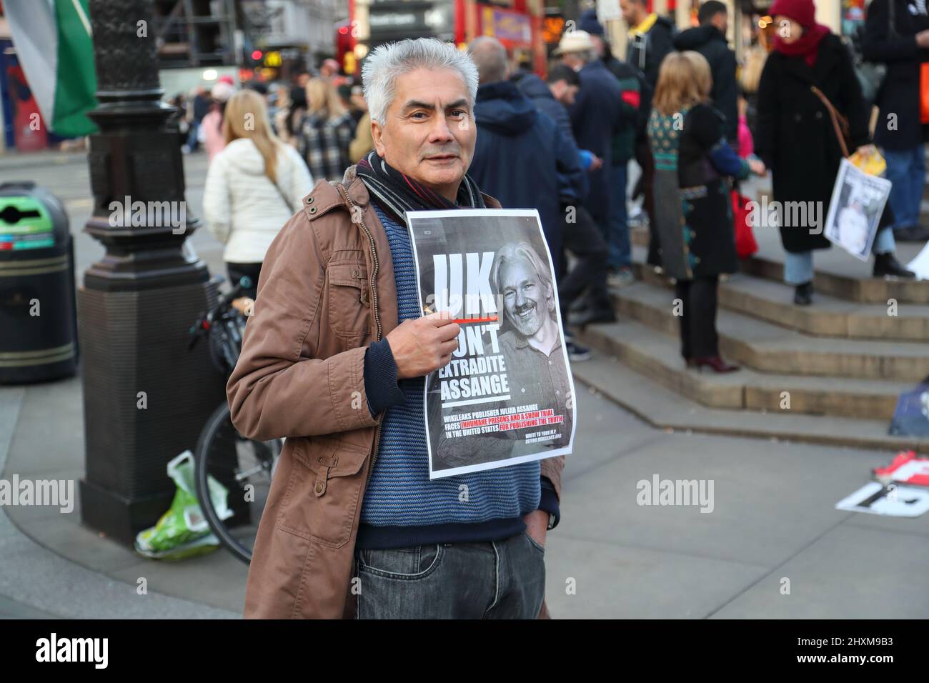 A small group of demonstrators holding placards campaign to free Julian Assange from prison at Piccadilly Circus, London, UK Stock Photo
