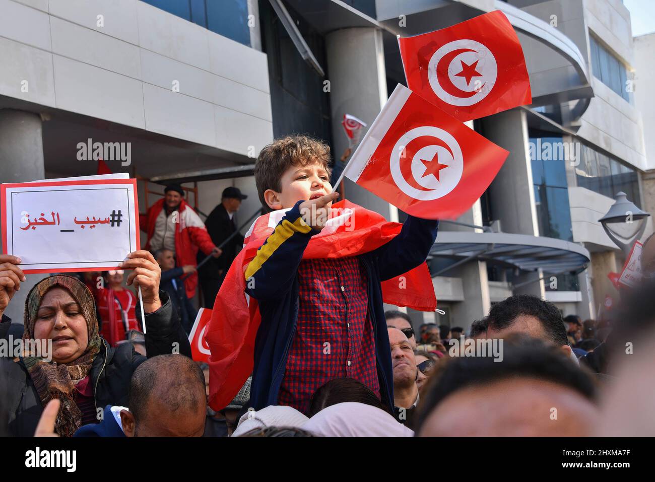 Tunis, Tunisia. 13th Mar, 2022. A kid waves Tunisian flags during the demonstration. Protesters march along Khair El-Din Pasha Street, to demand an accurate and official calendar to end the exceptional period by dissolving Parliament and calling for early legislative elections with purification of the electoral climate to prevent fraud in the will of voters. Credit: SOPA Images Limited/Alamy Live News Stock Photo