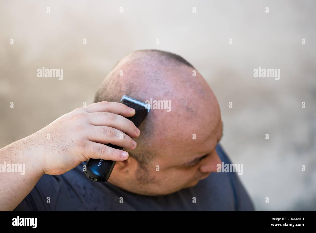 Male shaving or trimming his hair using a hair clipper or electric