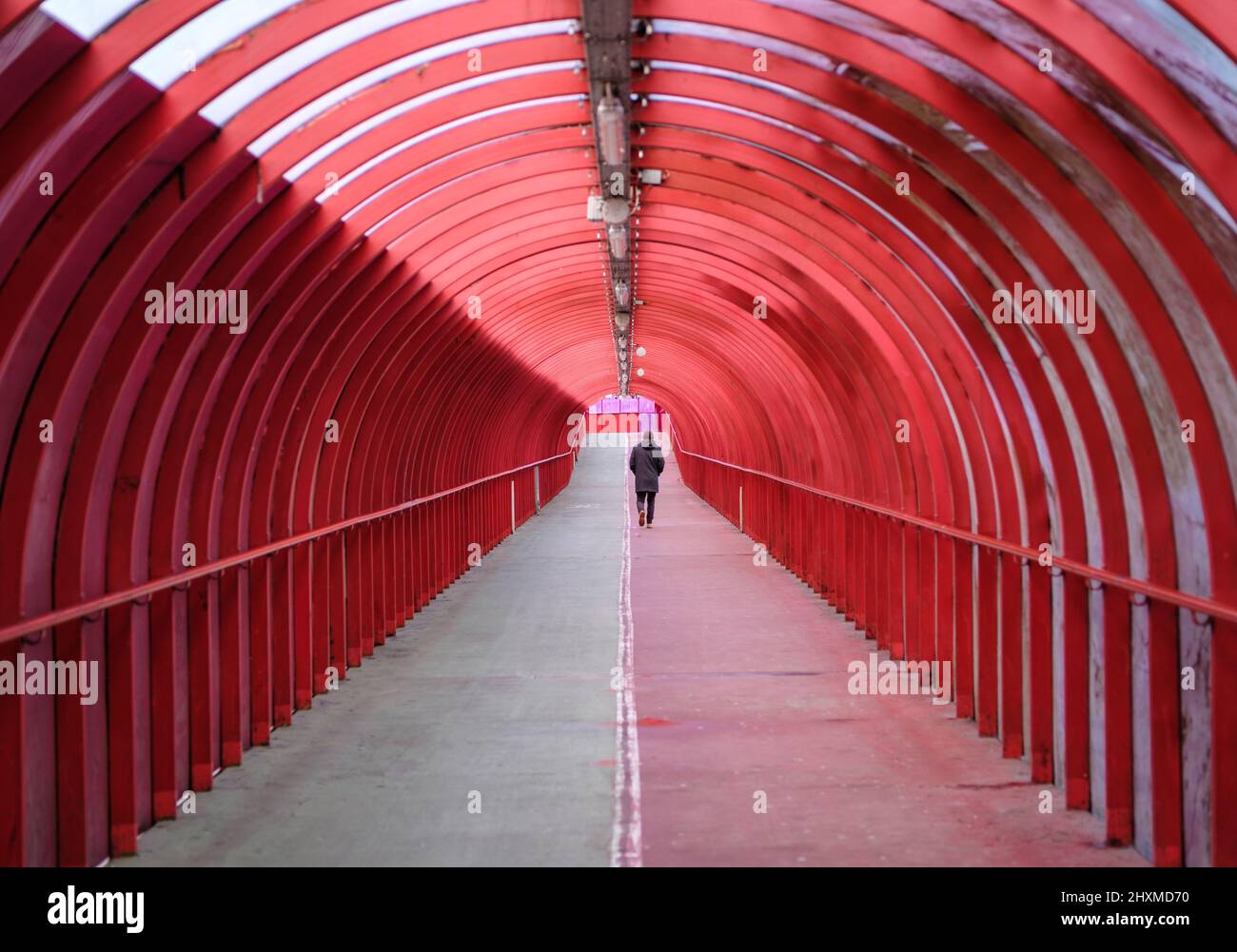 A Man Walking Alone Through A Covered Walkway At An Airport Or Train Station Stock Photo