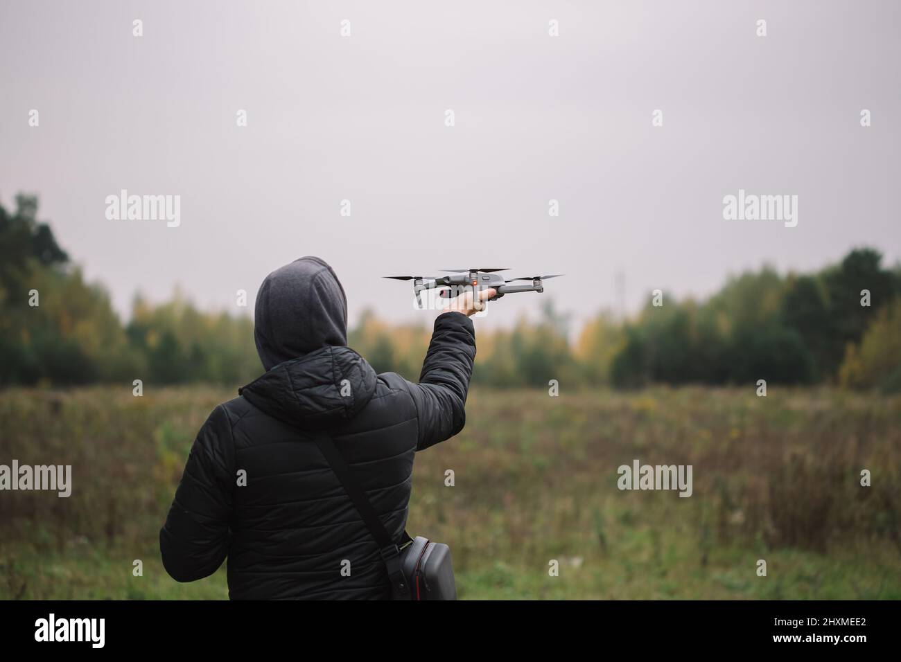 Man holding drone and remote control against field background. Stock Photo