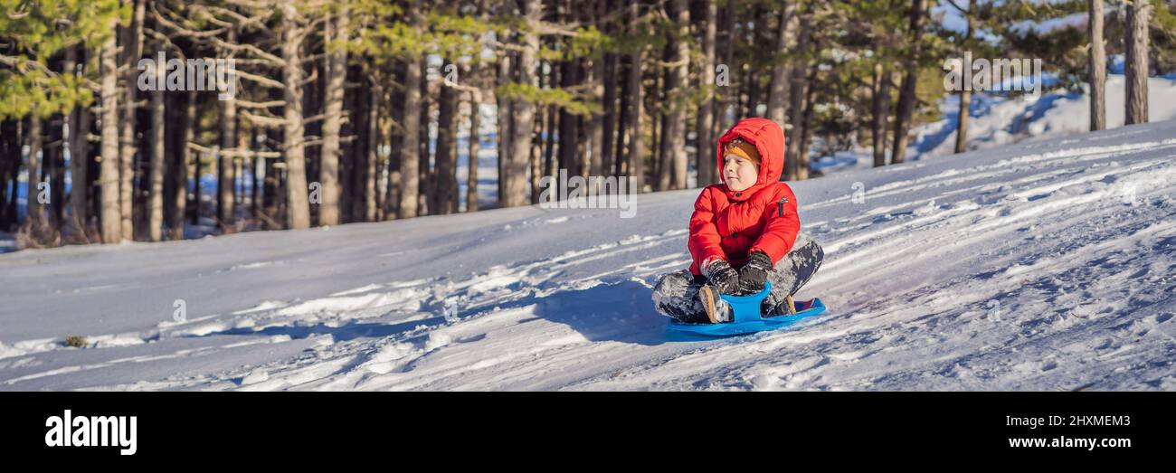 happy and positive little boy enjoying sledding and cold weather ...