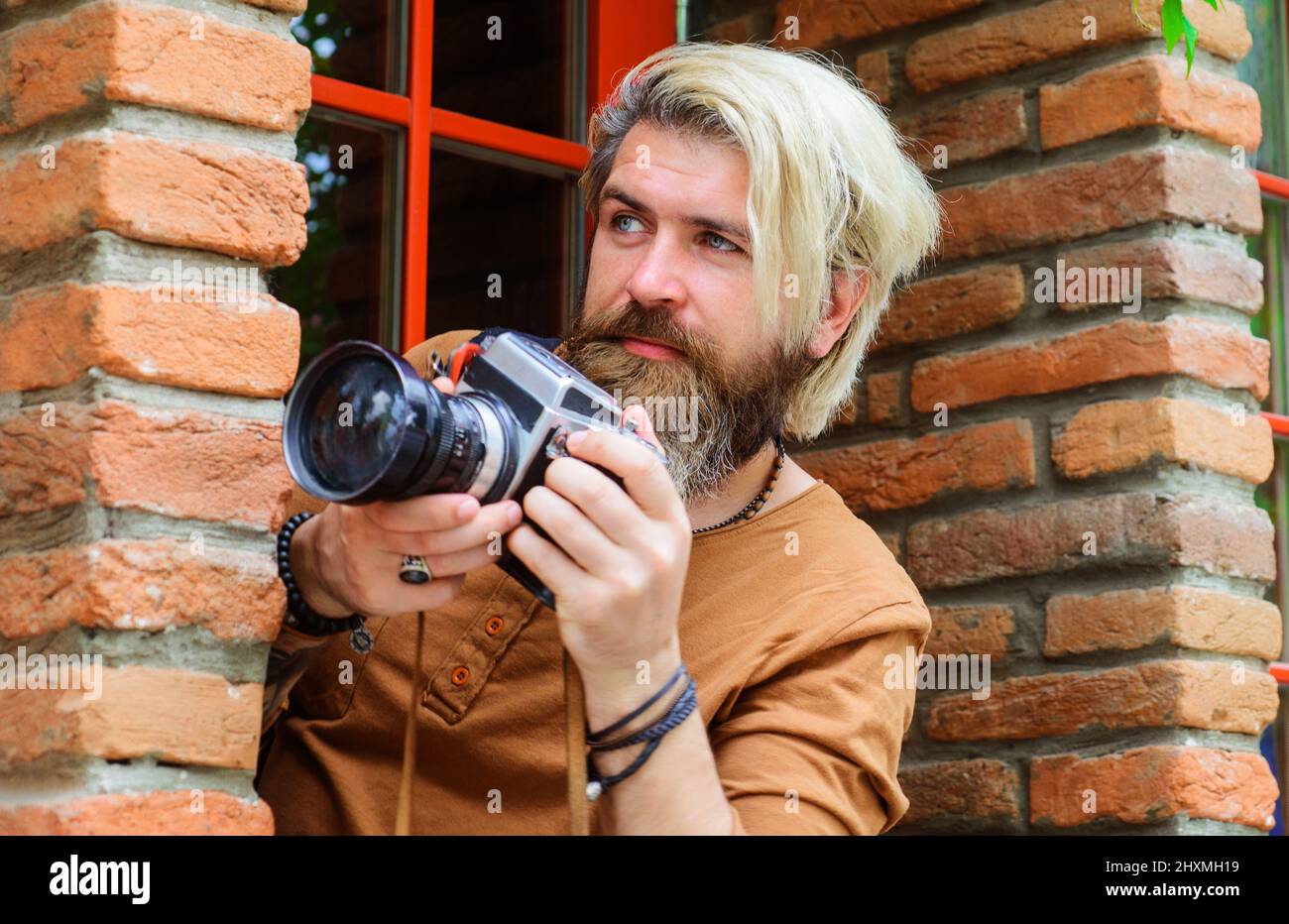 Paparazzi take picture with photocamera. Bearded Journalist with photo camera. Mass media. Detective. Stock Photo