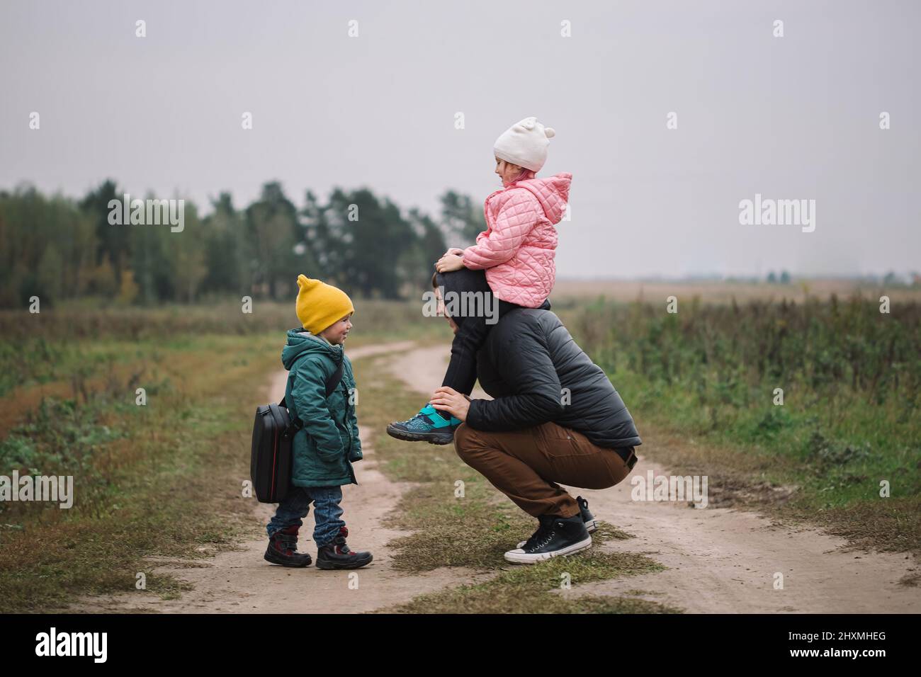 Happy family with two kids walking in the field autumn time. Dad carries his daughter on his shoulders. Stock Photo