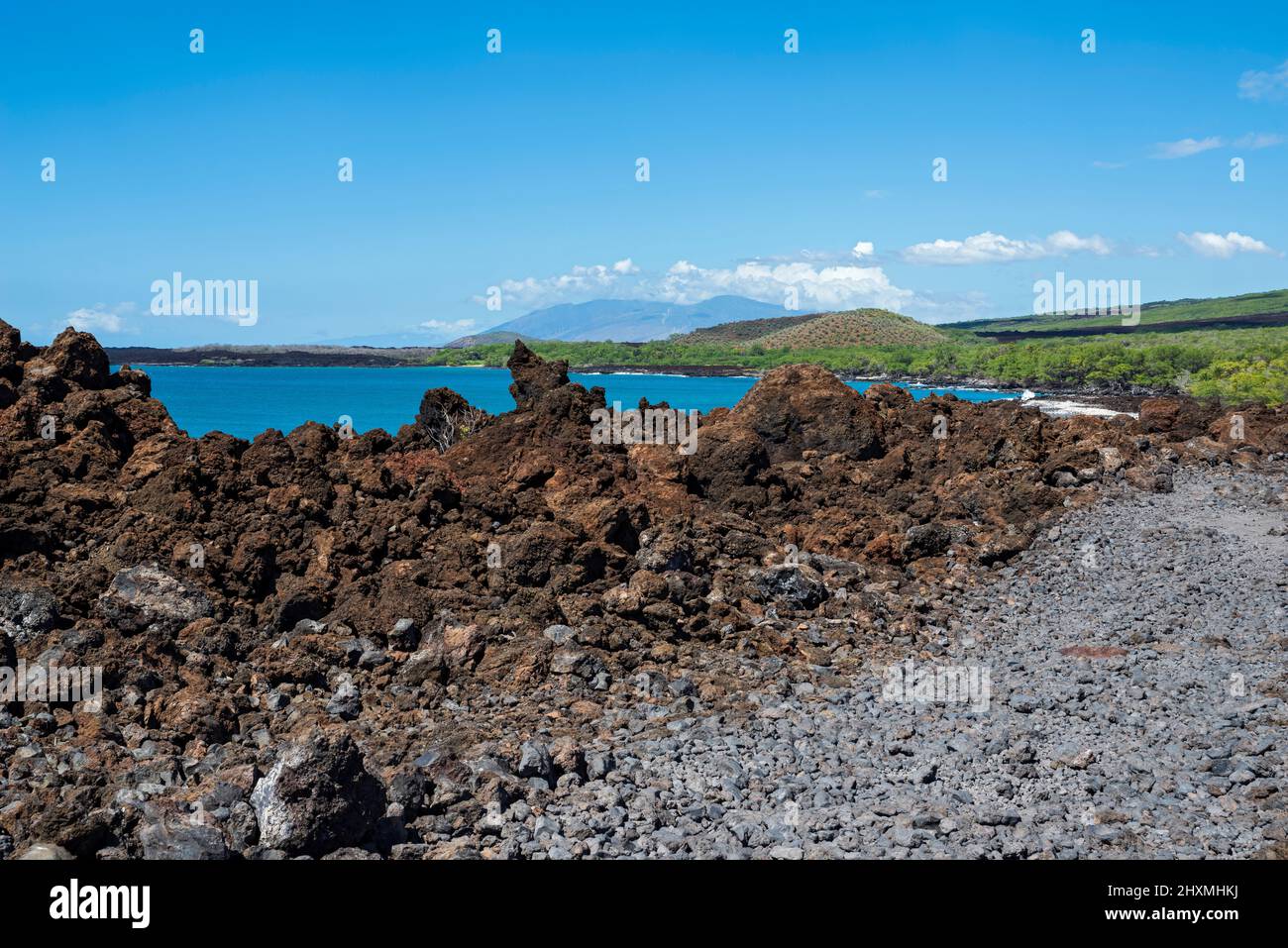 lava rock outcrop along trail at la perouse bay and west maui mountains on horizon Stock Photo