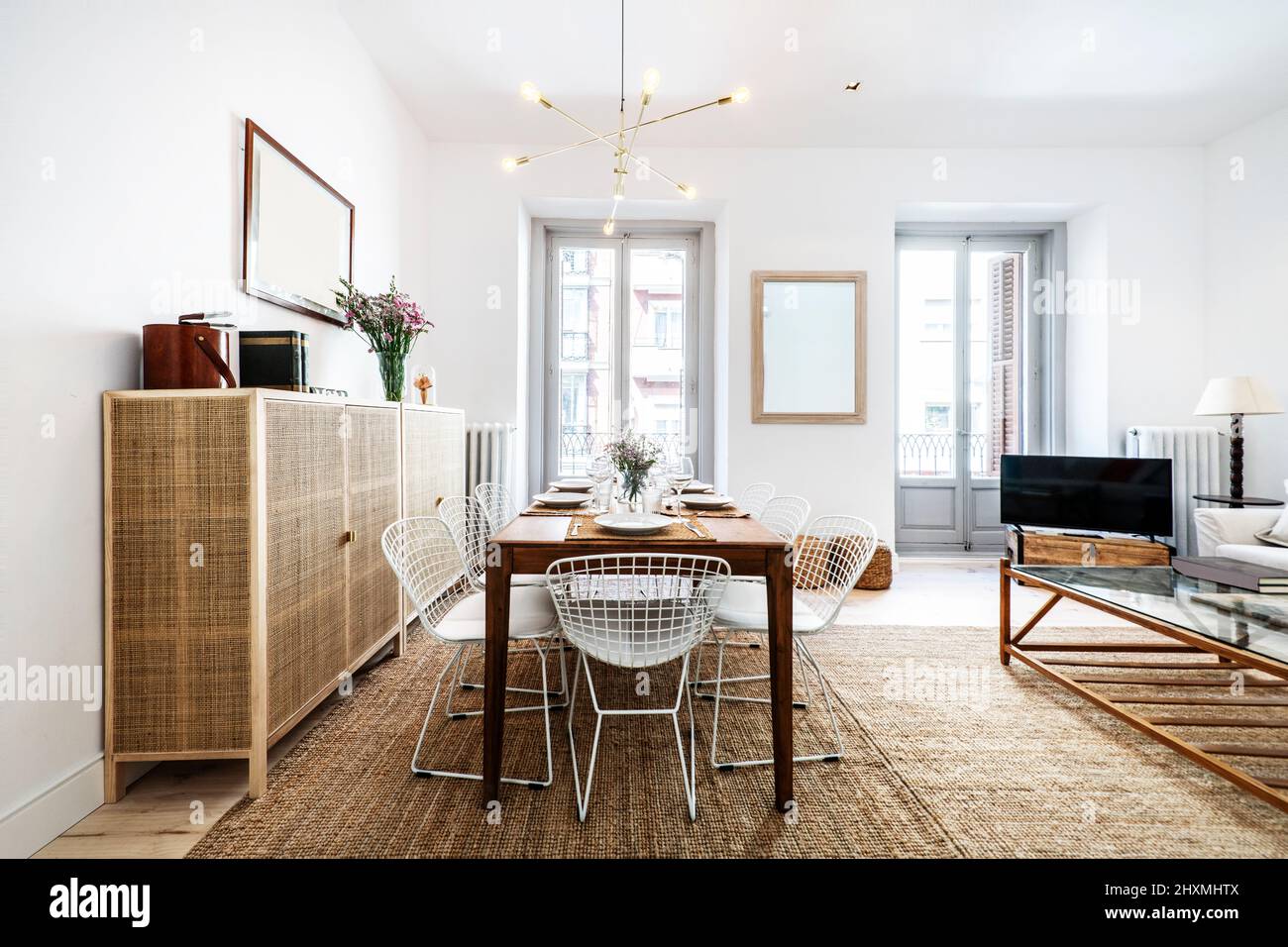 This room with a wooden dining table with white metal chairs and a mesh