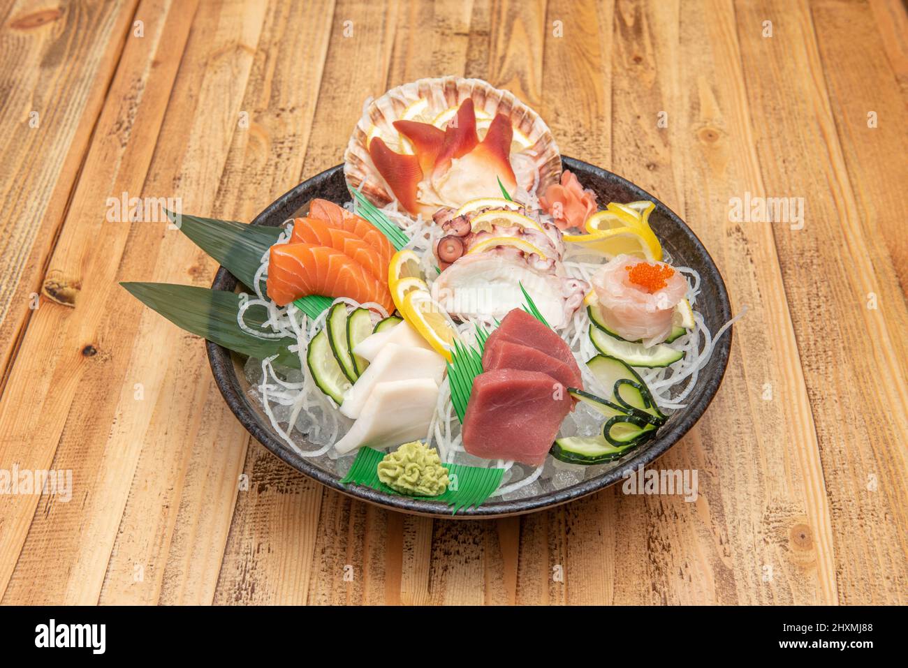 Round tray of sushi, octopus sashimi, butterfish, bluefin tuna, Norwegian salmon and scallops with wasabi and ginger Stock Photo