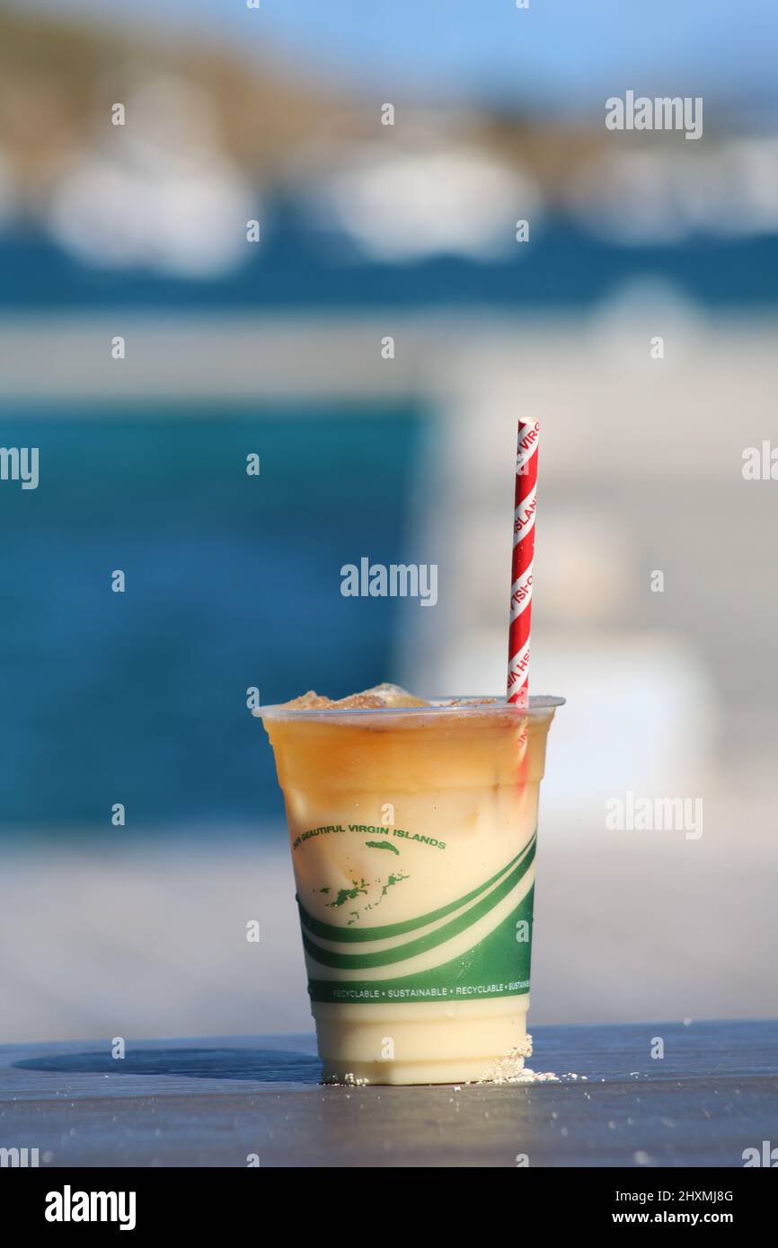 Painkiller rum cocktail on beach in British Virgin Islands in the Caribbean with logo on cup Stock Photo