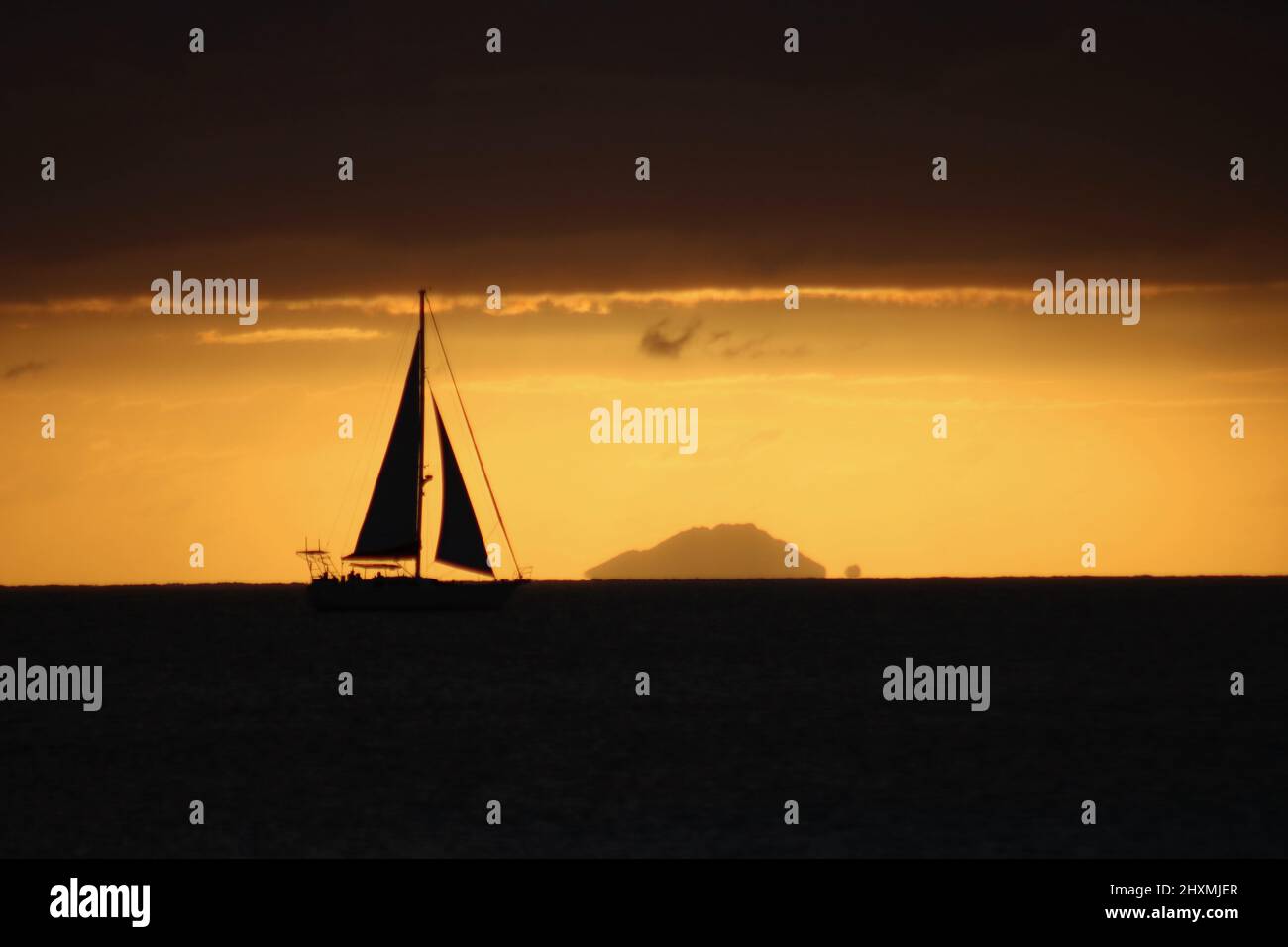 Black Silhouette of a yacht against a Caribbean sunset on Antigua and Barbuda Stock Photo