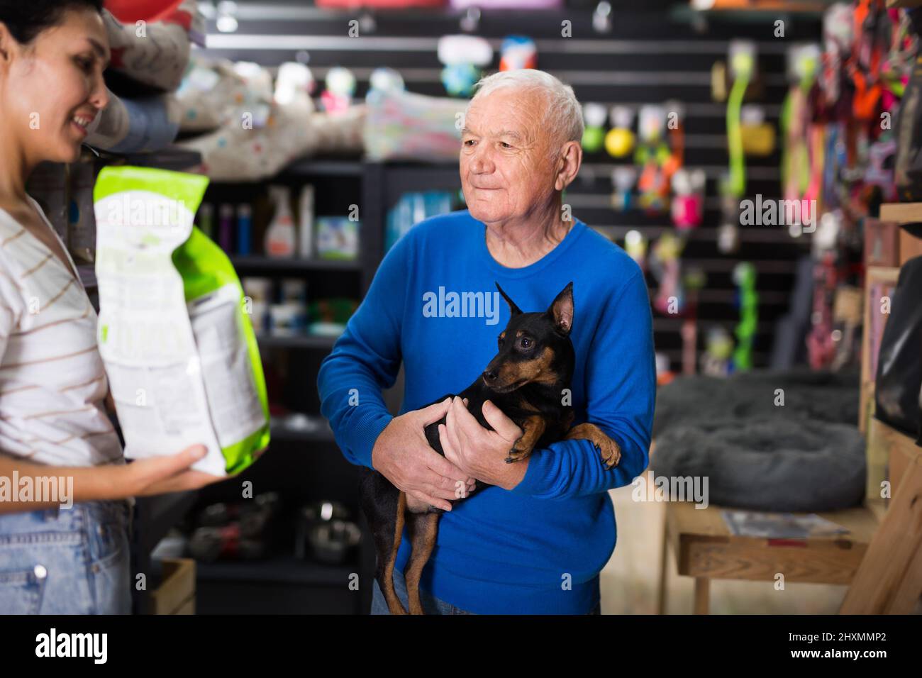 Pet store employee helps an elderly man choose dog food Stock Photo Alamy
