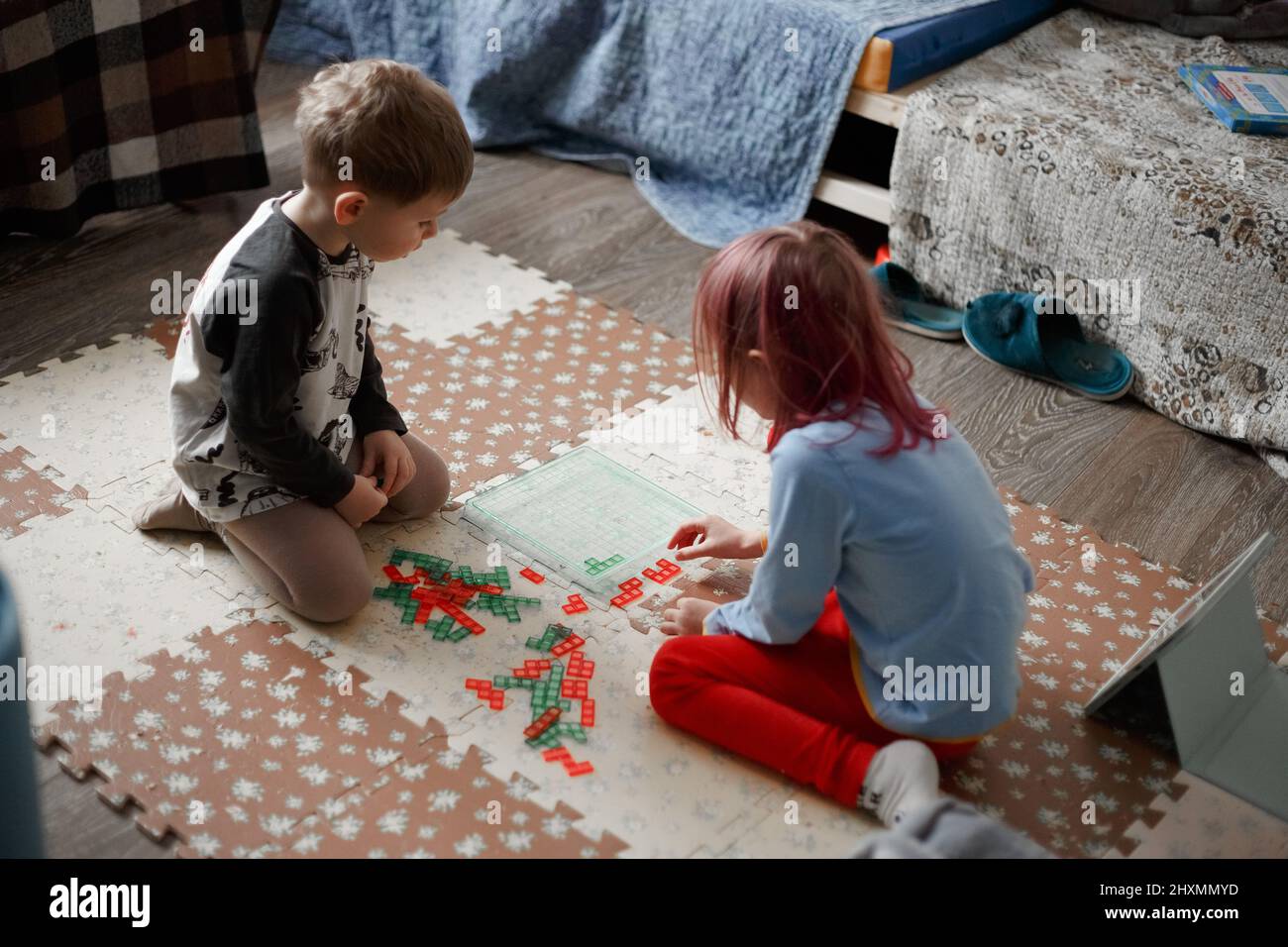 Little caucasian kids playing a board game on the floor in their room