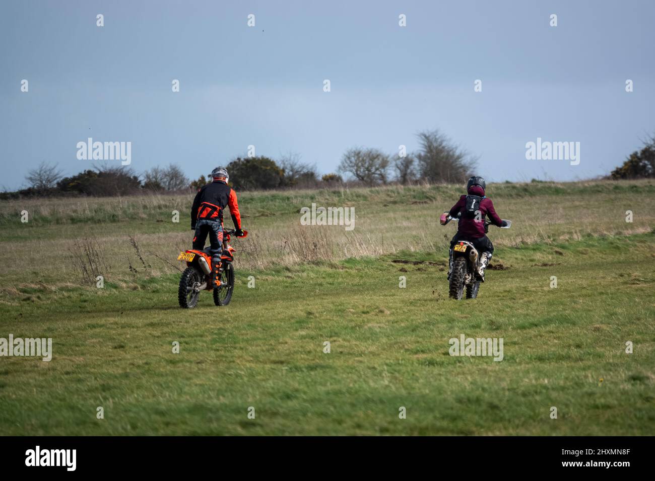 a pair of motor cyclists (bikers) riding off-road motorbikes across ...