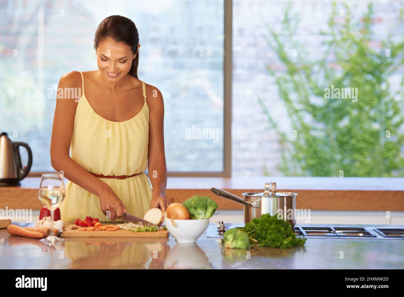 Soupy goodness. A young woman cutting vegetables in the kitchen. Stock Photo