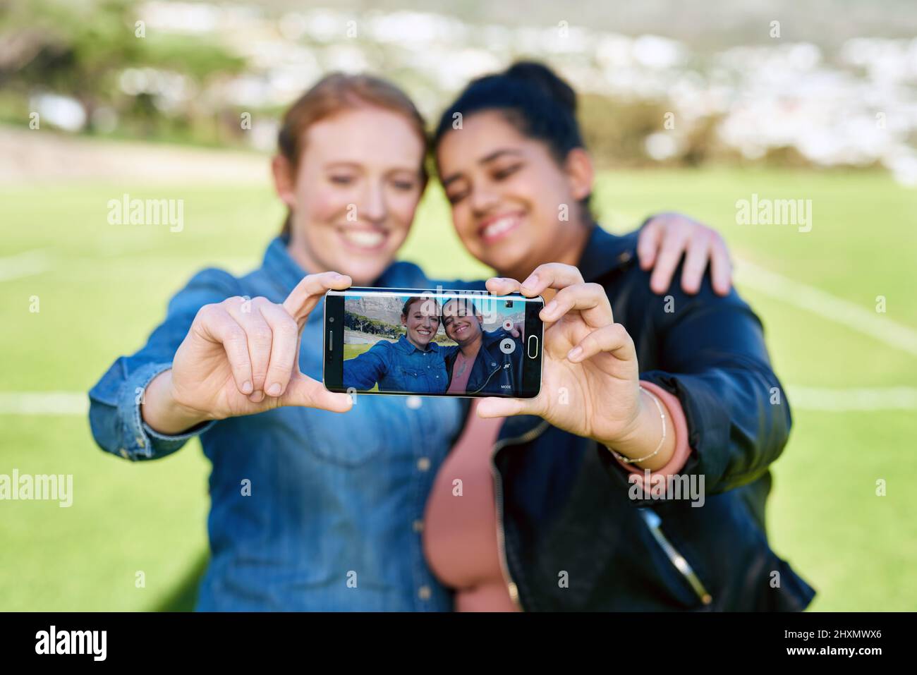 We have to capture our friendship together. Shot of female friends taking a picture together outside. Stock Photo