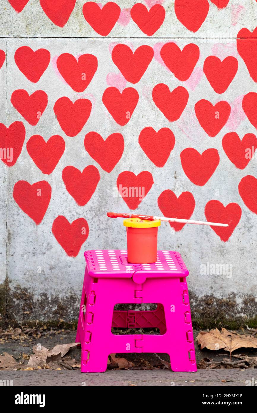 A pot of masonry paint propped on top of a stool by a volunteer.   29th March 2022 marks the one year anniversary of the first heart being drawn on th Stock Photo