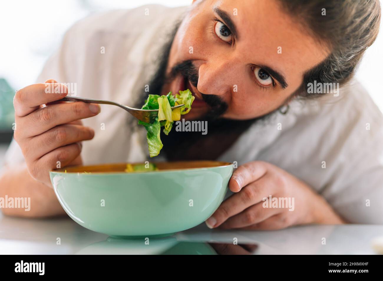 Close-up of a bearded young man eating a salad Stock Photo