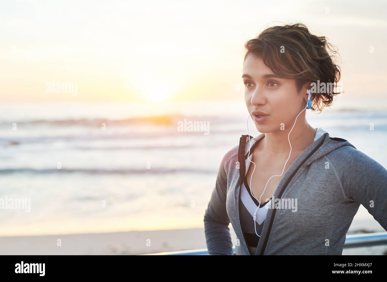 Catch your breath then chase it again. Cropped shot of a young woman wearing earphones while out for a run. Stock Photo