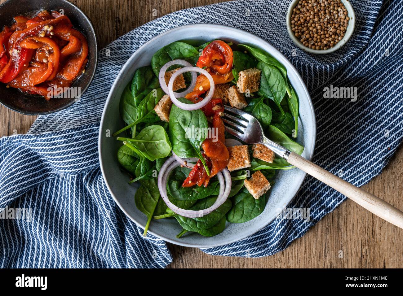 Healthy spinach salad with roasted red pepper on rustic wooden table. Stock Photo