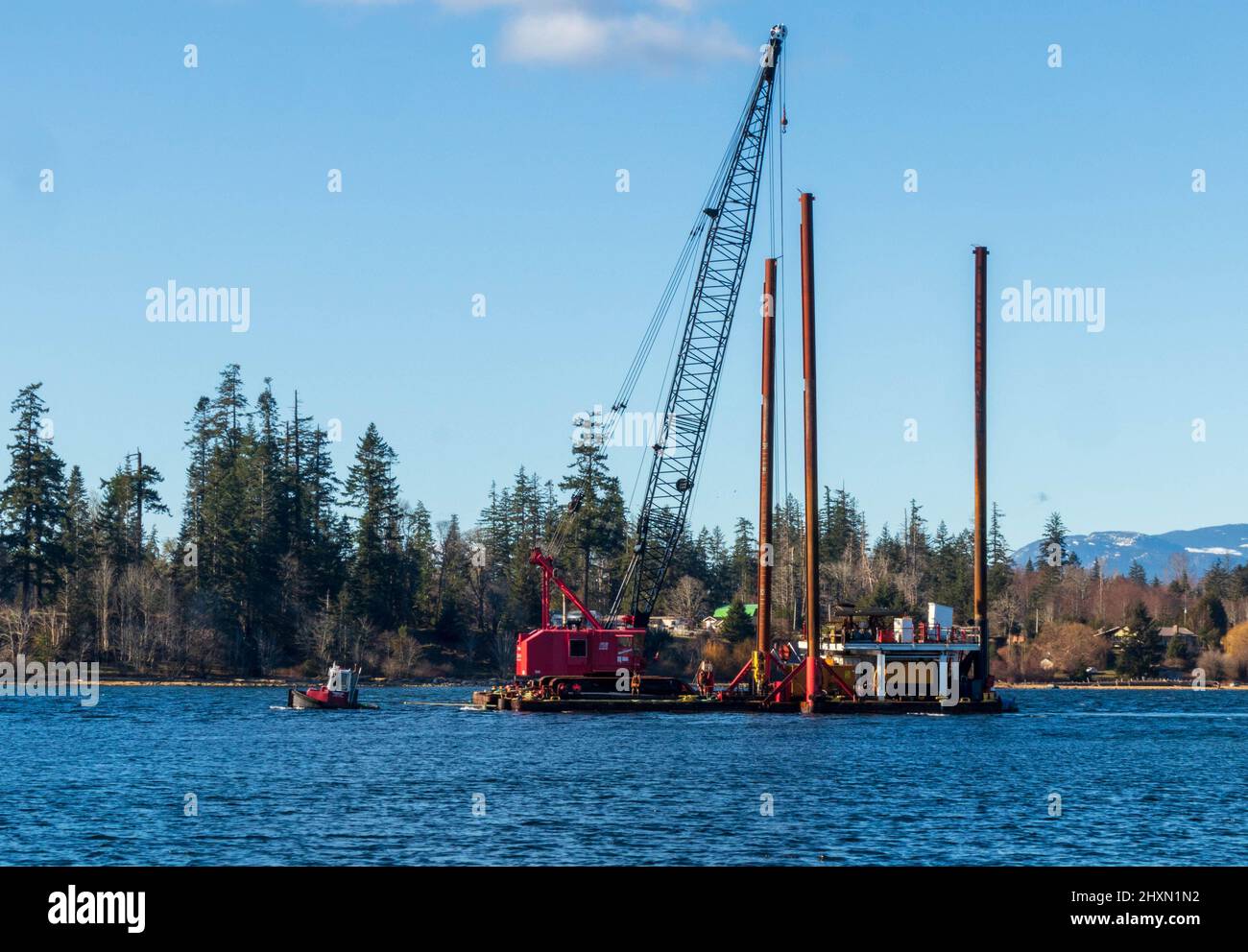 Small tow boat hauling barge and pile driver on Vancouver Island. Stock Photo