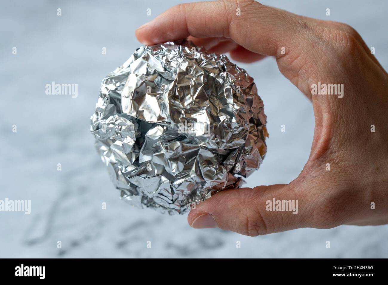 Wrinkled ball of aluminium foil, a material often used in the kitchen. Stock Photo