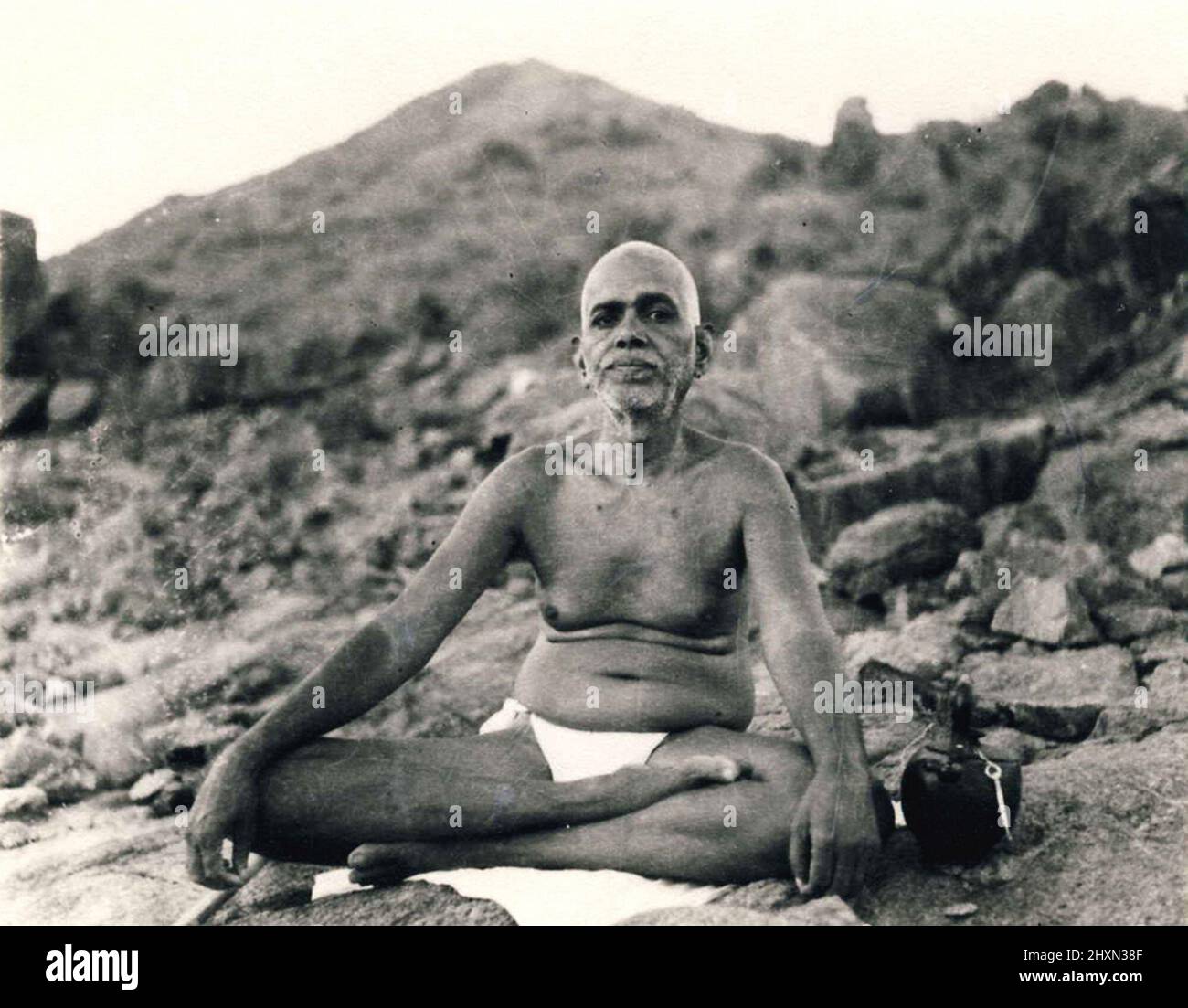 Vintage black and white photograph of Indian Hindu holy man Sri Ramana Maharshi sitting outside with Arunachala Hill in the background,  Tiruvannamalai, India Stock Photo