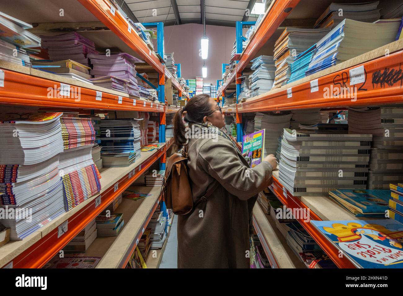 A lady browses through books at a wholesale warehouse where books are