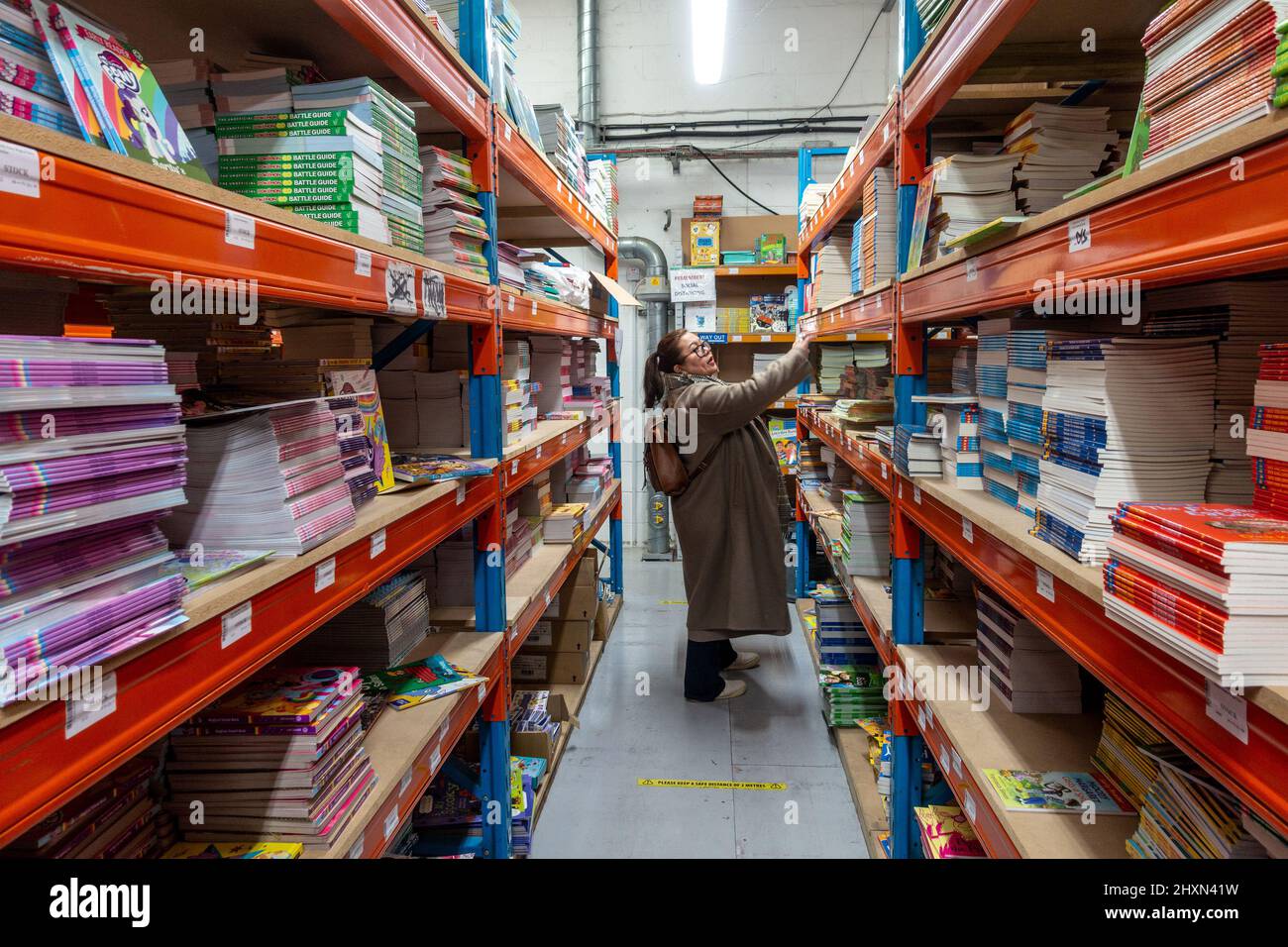A lady browses through books at a wholesale warehouse where books are