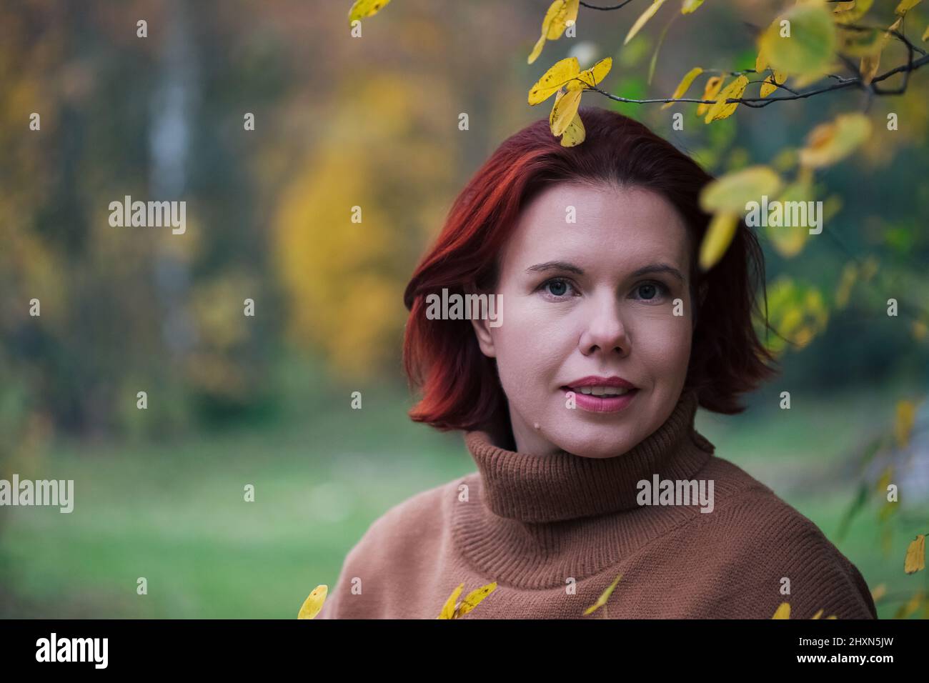 Portrait Of A Mature Woman against yellow forest trees in the autumn Stock Photo