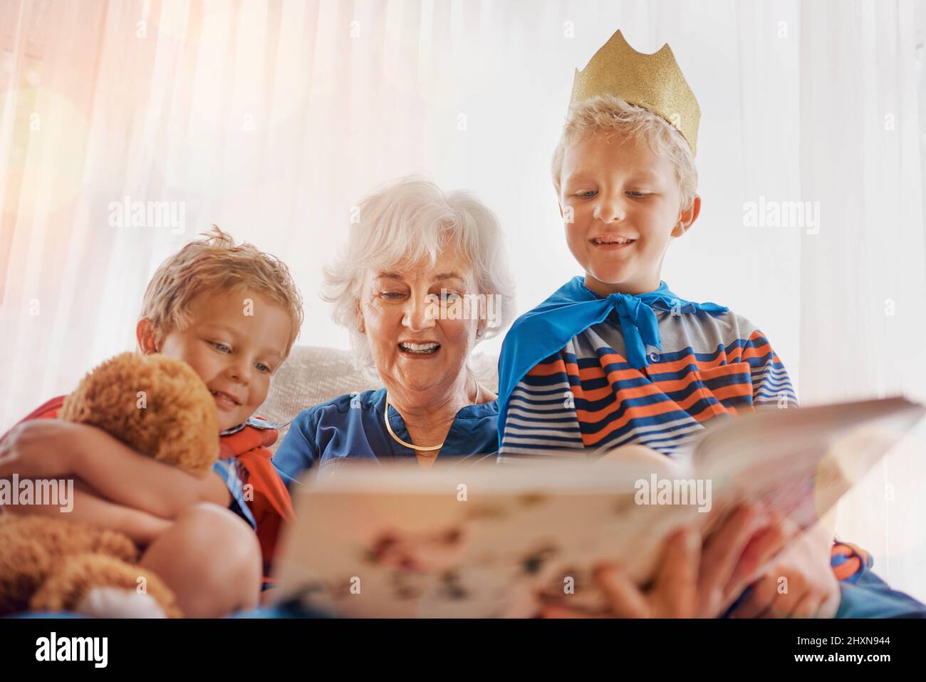 Granny is reading our favorite story again. Shot of a senior woman spending time wither her grandsons. Stock Photo