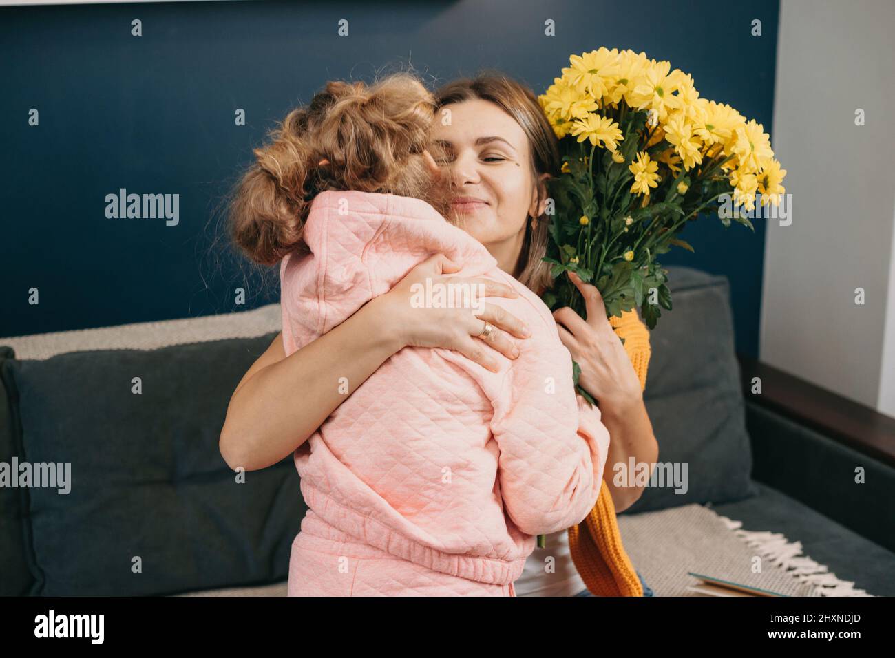 Caucasian mother feeling grateful embracing her little girl giving her