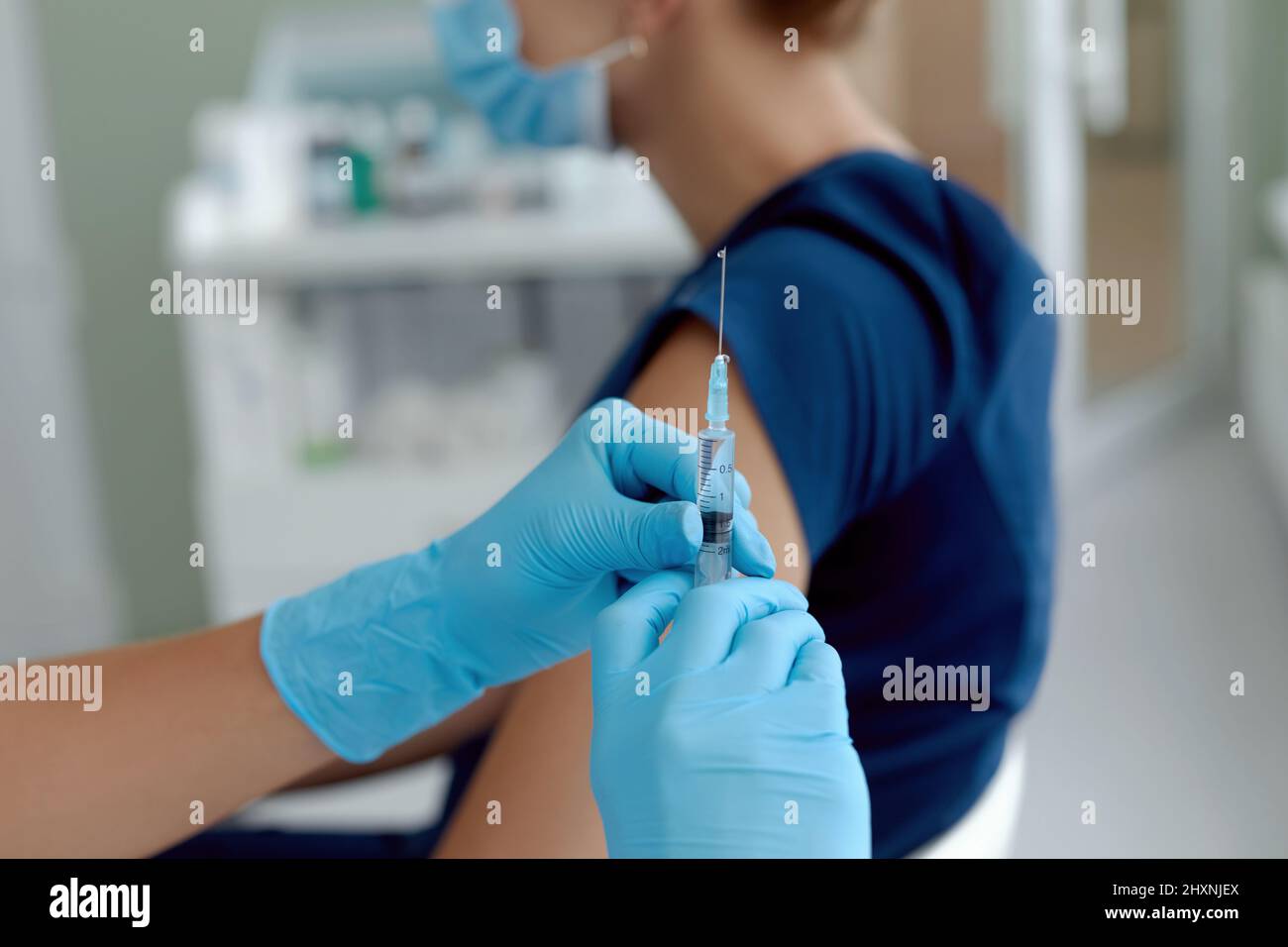 close up doctor holding syringe  make injection to patient in medical mask. Covid-19 or coronavirus vaccine Stock Photo