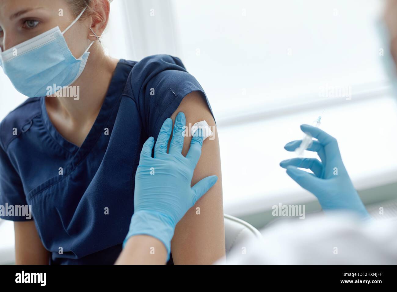 Vaccination, disease prevention concept. Woman in medical face mask getting Covid-19 vaccine. nurse giving flu injection to patient Stock Photo