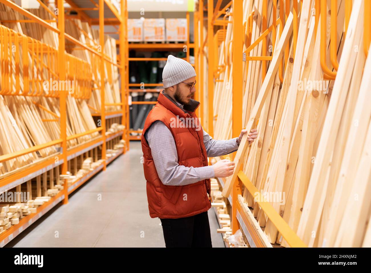 a customer in a lumber store chooses bars and boards for a frame house ...