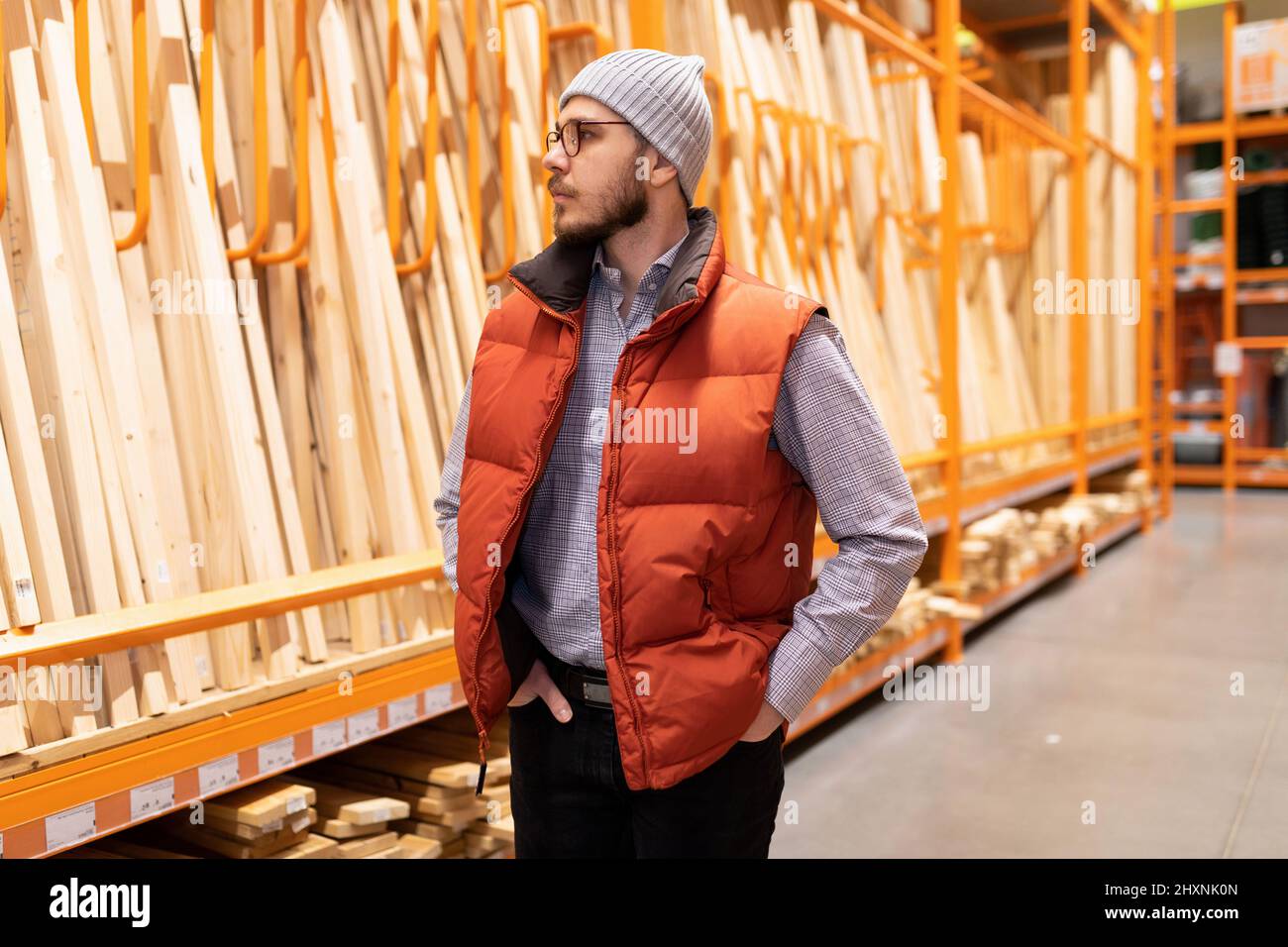 a carpenter in a lumber hardware store chooses wooden bars and boards