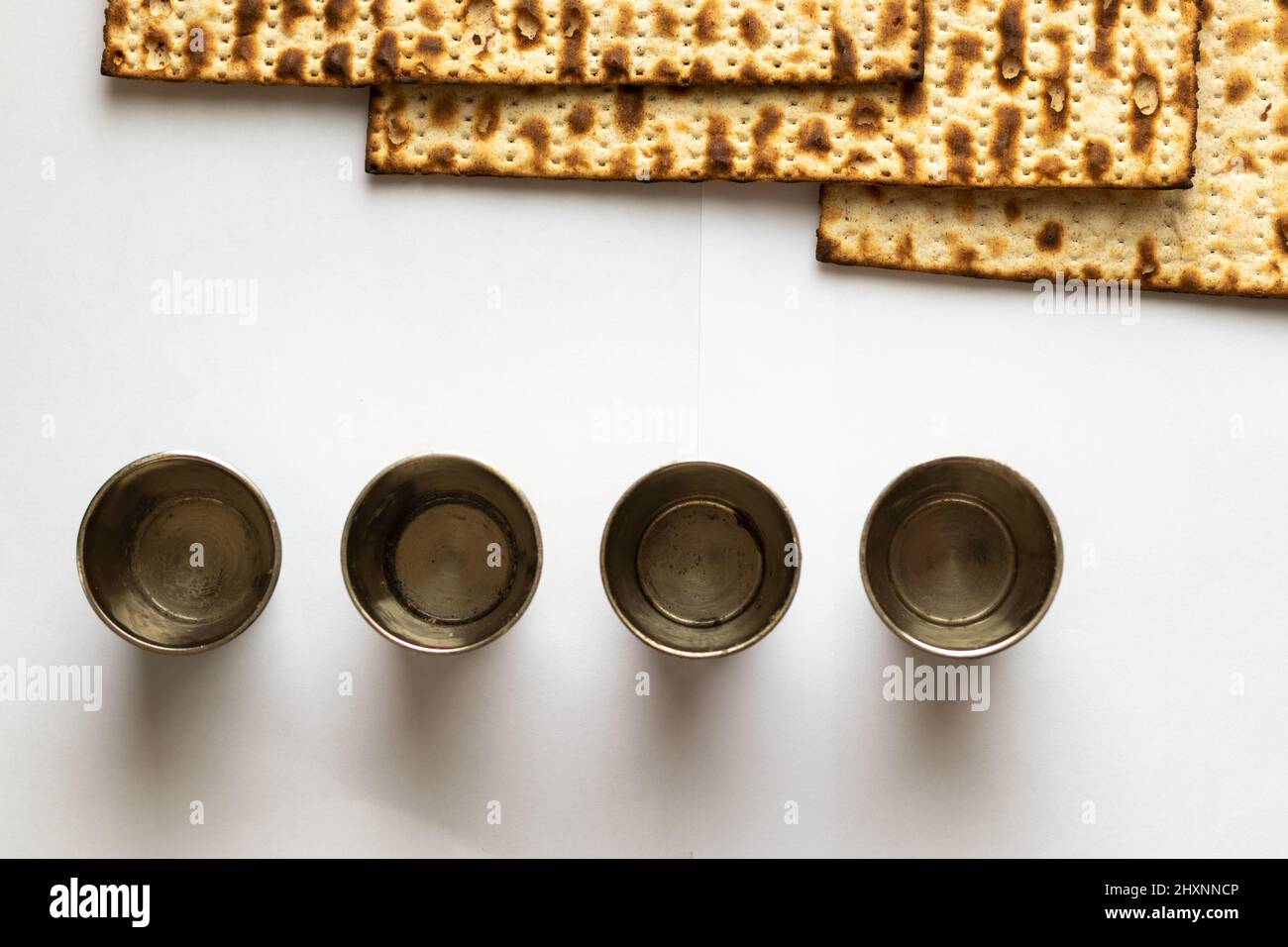 Three matzahs Jewish bread for Passover. Next to four little silver