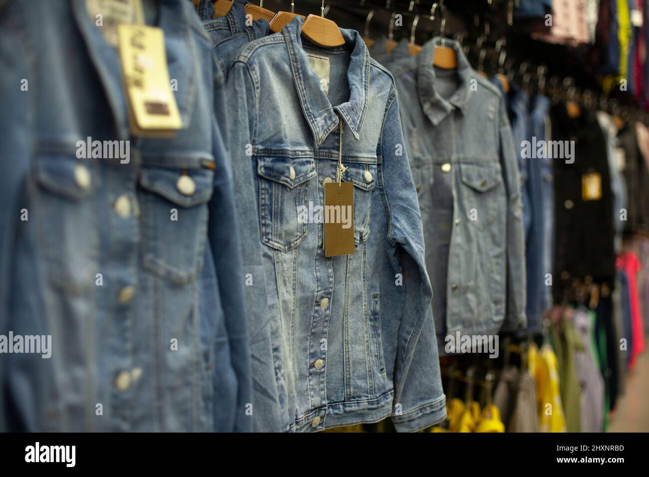 Denim jacket hangs on hanger in store. Details of clothing sales. Things for children and adults in shopping center. Clothes for every day. Stock Photo