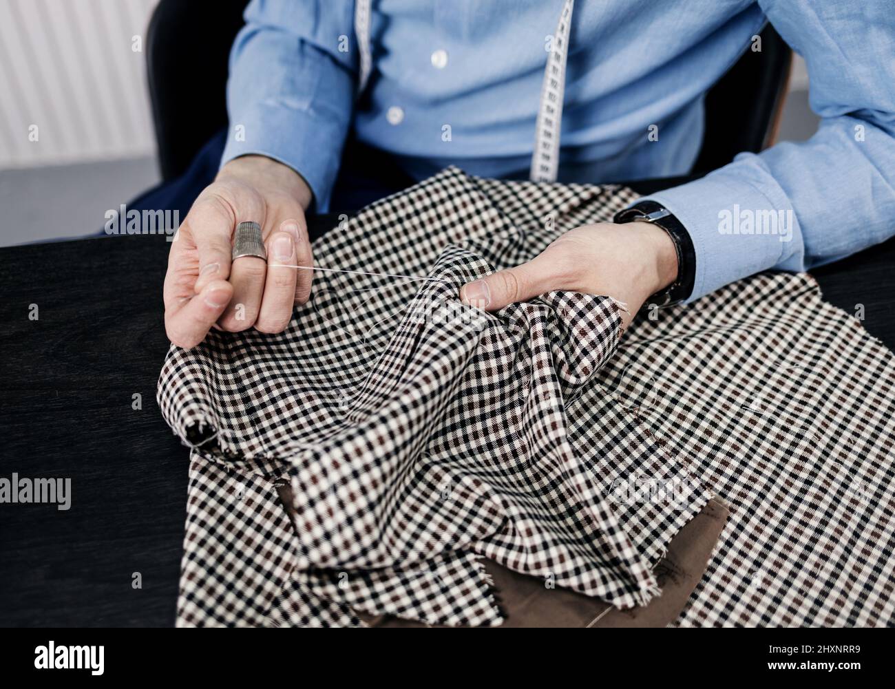 Closeup partial view of man sewing cloth with needle and thread with